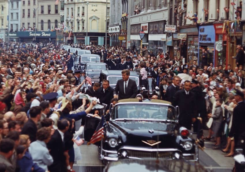 President John F. Kennedy greets spectators as he travels in his motorcade in Patrick Street, Cork, Ireland. 28 June 1963. Robert Knudsen.