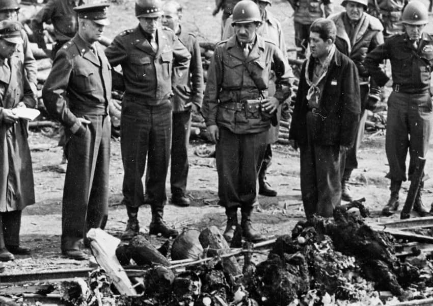 General Dwight Eisenhower and a party of high ranking U.S. Army officers, including Generals Bradley, Patton, and Eddy, view the charred remains of prisoners that were burned upon a section of railroad track during the evacuation of the camp. April 12, 1945.